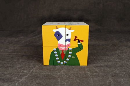 Cube puzzle showing a colourful illustration of a cow with human features on a grey background.  