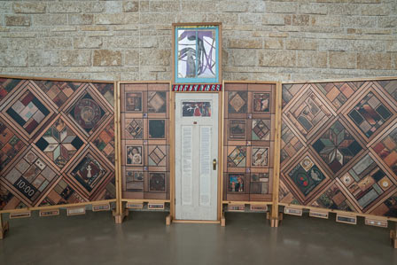 A white door decorated with text and images flanked by vertical wood panels covered in patterns of images. 