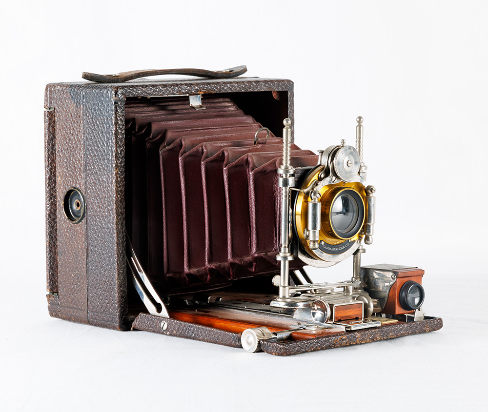 Colour image of a folding camera with metal and wood hardware, leather bellows and exterior.