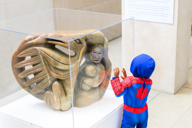 Guest dressed in Spiderman costume looking at an art display