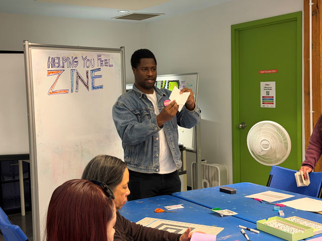 Artist showing a group how to make zine